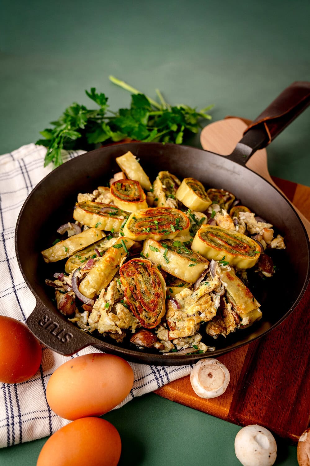 Fresh wild herb pancakes in a pan with vegetables, eggs and spices.