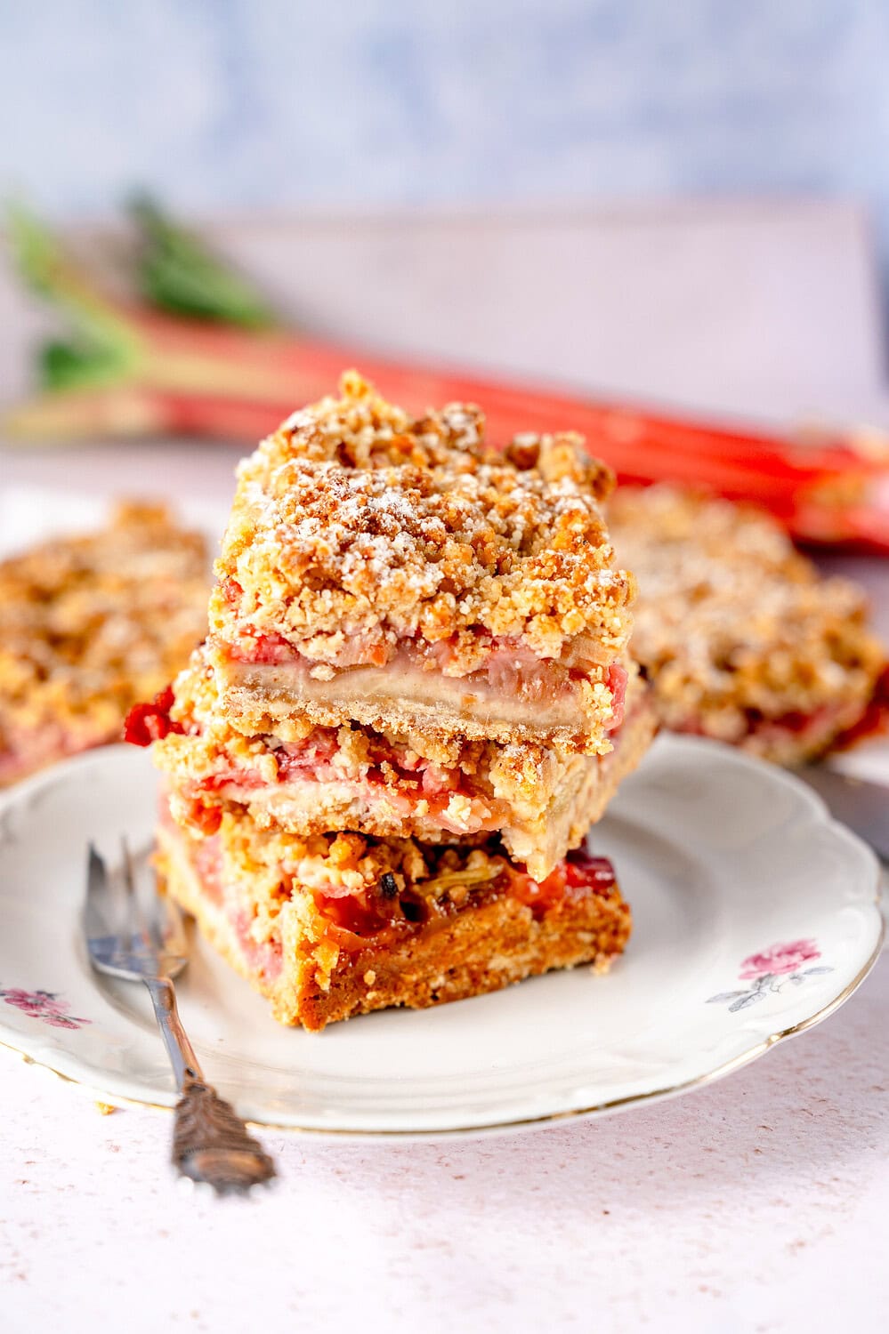 Three pieces of rhubarb crumble cake with brown butter stacked on cake plate