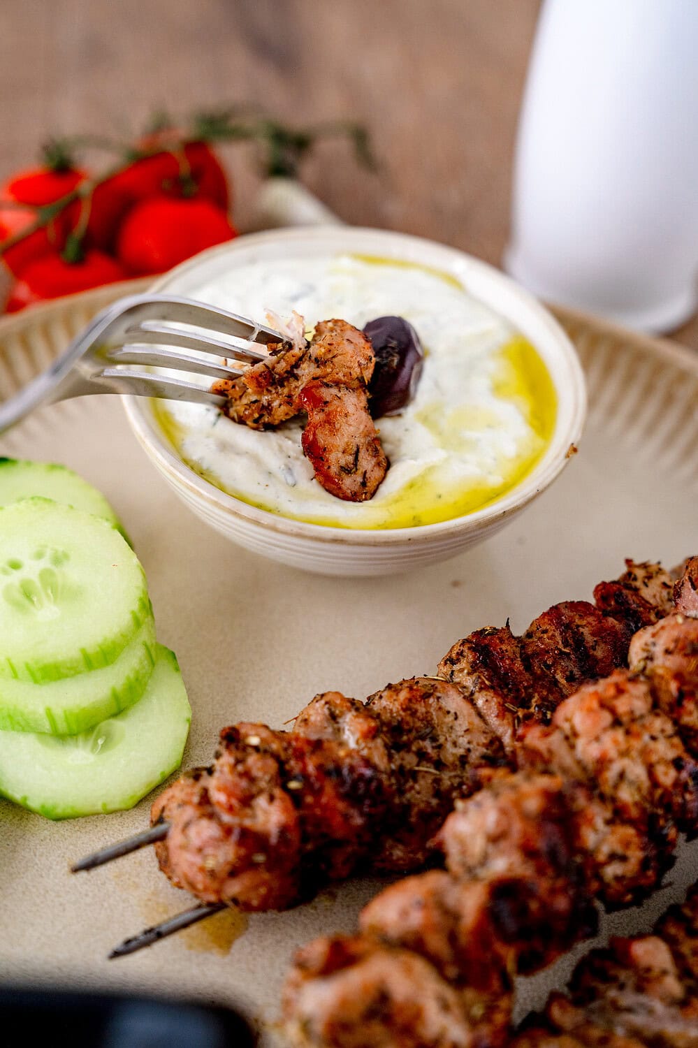 A piece of the gyro grill skewer is dipped in tzatziki