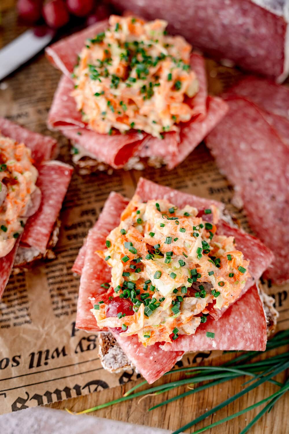 Close-up of a Smörrebröd with Aoste Le Briedu salami and a topping of carrots, apples and chives