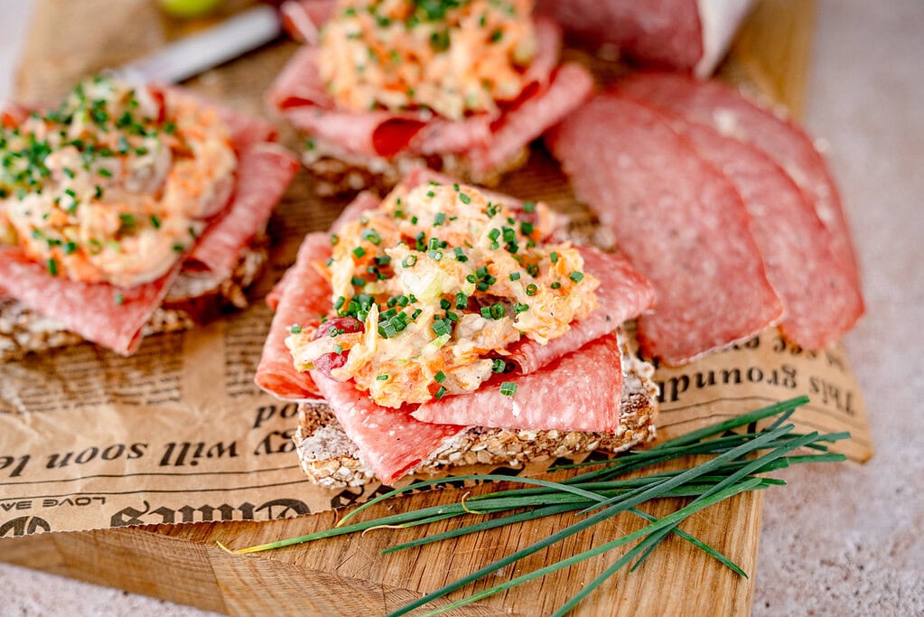 Smörrebröd with salami and a topping of carrots, apples and chives