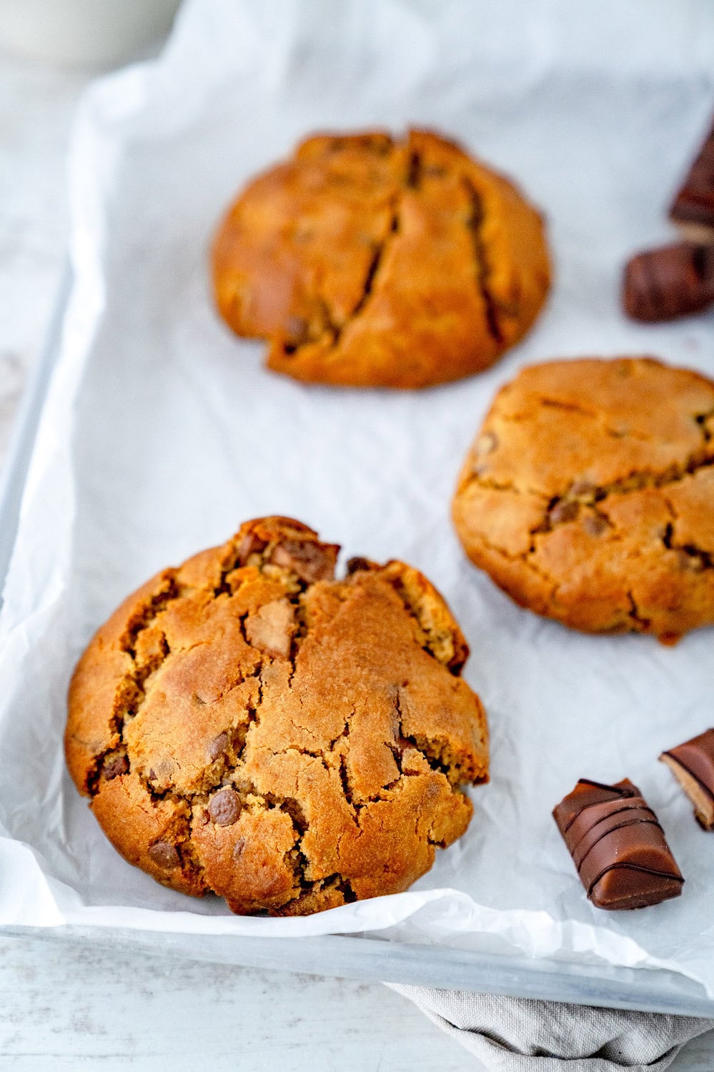 Drei Nutella Cookies aus der Heißluftfritteuse auf einem Backblech mit weißem Backpapier platziert