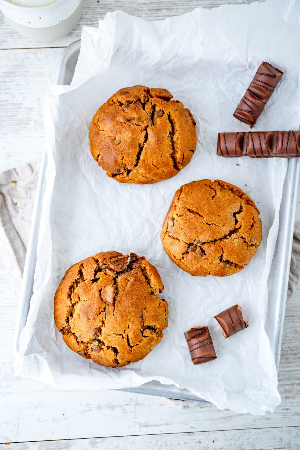 Mehrere Nutella Cookies aus der Heißluftfritteuse mit Schokoriegeln auf weißem Backpapier