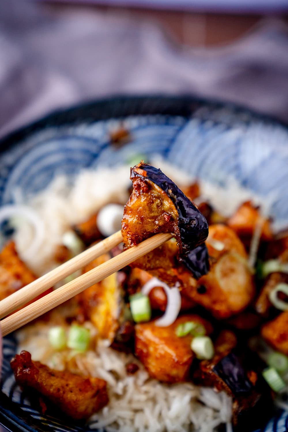 Frittiertes Stück Aubergine zwischen zwei Essstäbchen