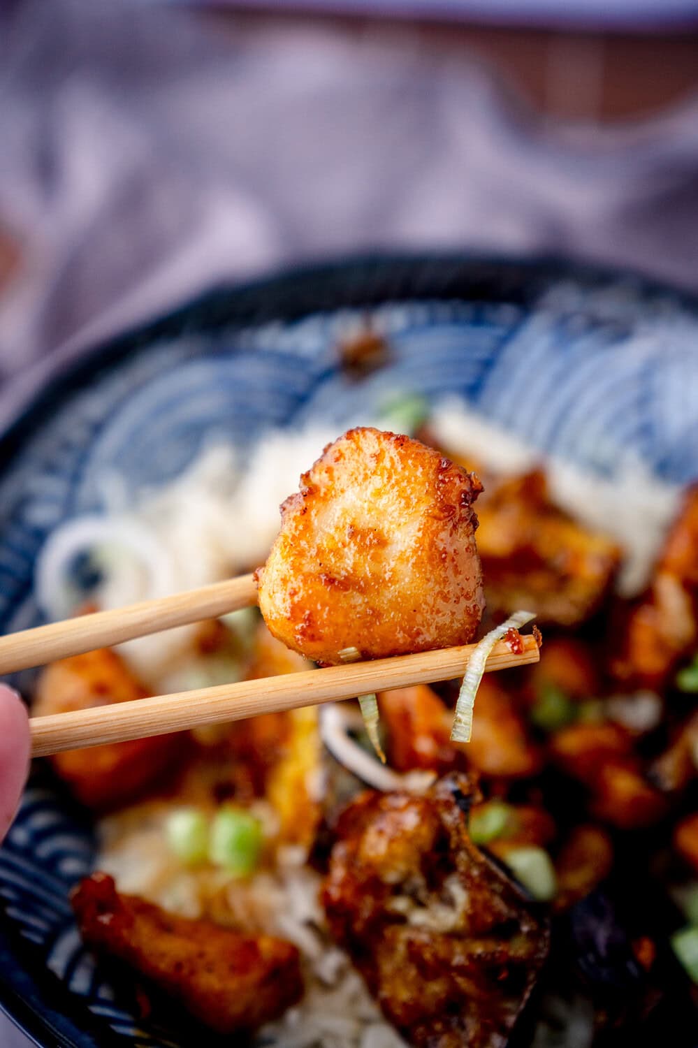 Frittiertes Stück Hähnchenfleisch zwischen zwei Essstäbchen