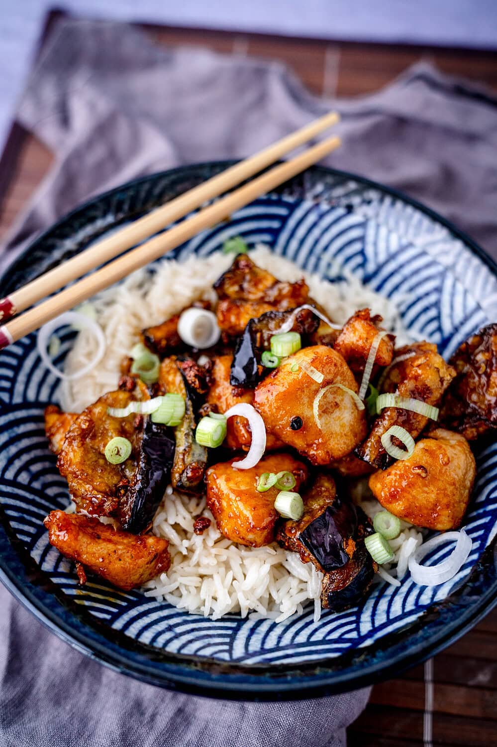 Asiatisch frittierte Auberginen mit Hähnchenfleisch und Reis in einer Schale mit Essstäbchen