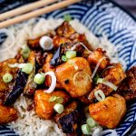 Asiatisch frittierte Auberginen mit Hähnchenfleisch und Reis in einer Schale mit Essstäbchen von schräg oben im Querformat