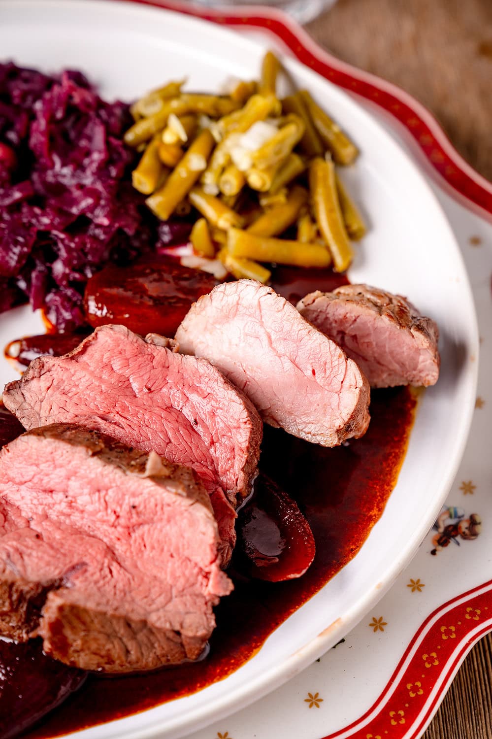 Schweinefilet Rinderfilet in dunkler Rotweinsauce auf Weihnachtsteller mit Bohnensalat und Rotkohl