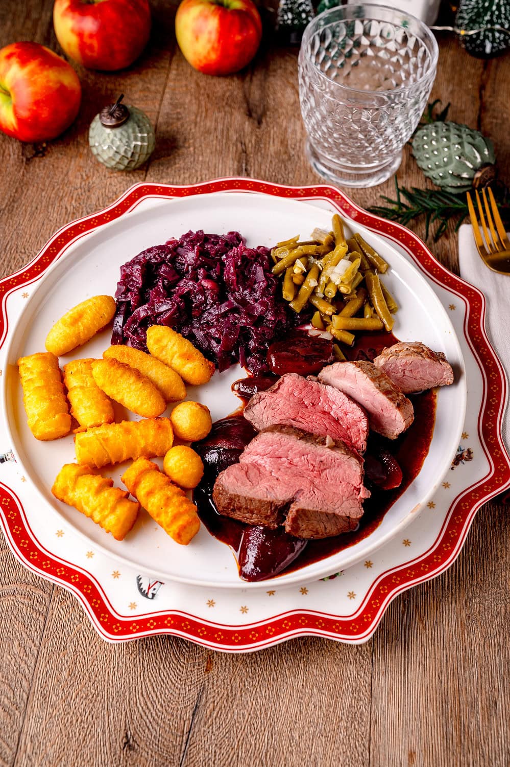 Weihnachtsteller mit Rinderfilet Schweinefilet Filet in dunkler Rotweinsauce, beilagen sind Kroketten Rotkohl und Bohnensalat