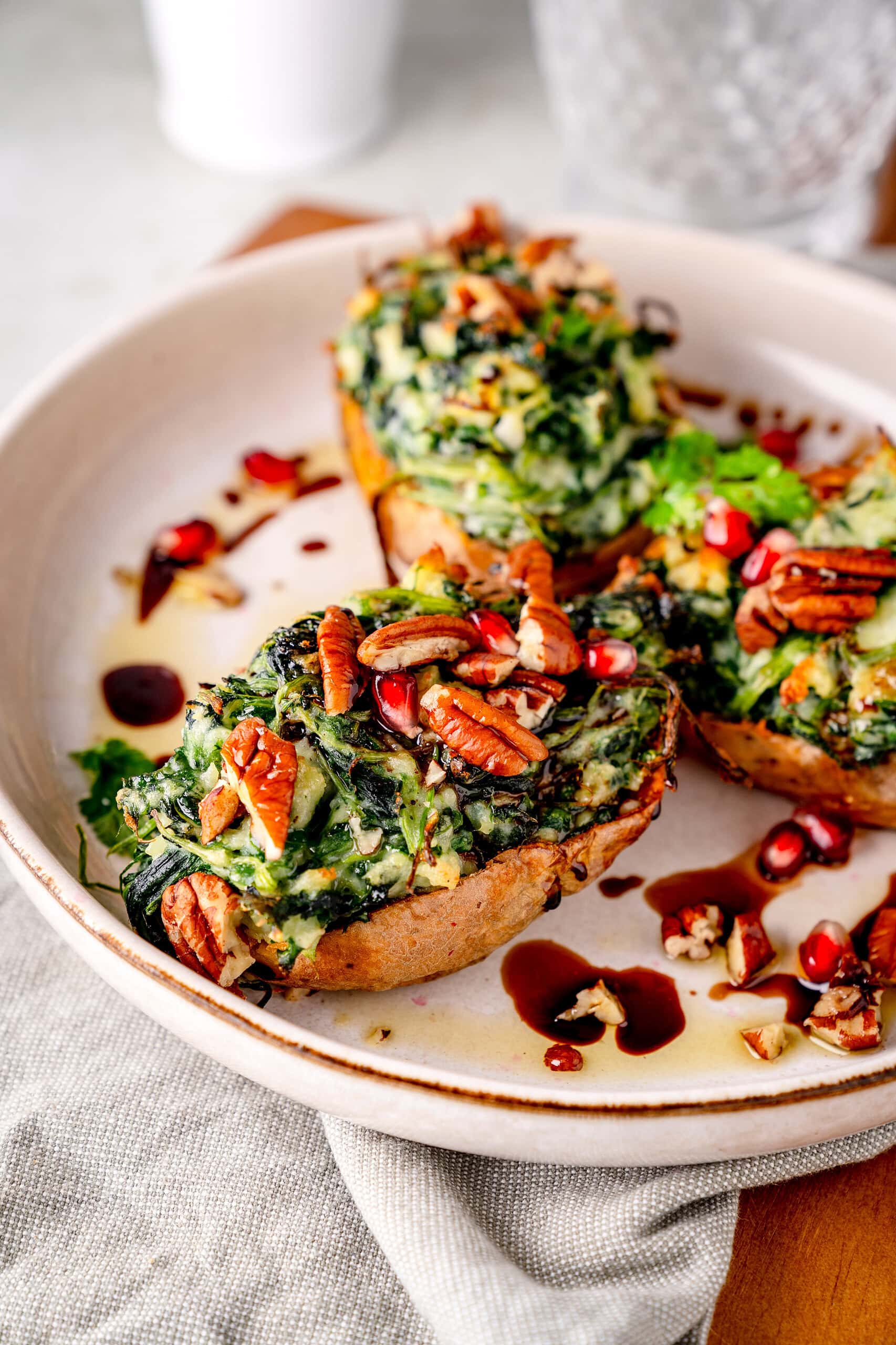 Gebackene Ofenkartoffeln mit, Nüssen und Granatapfelkernen auf einen weißen Teller.