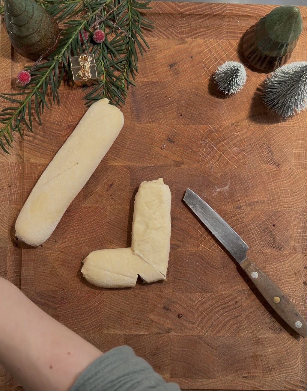 Geschälte Eierkäse auf einem Holztisch mit Küchenmesser und Dekorationszweigen.