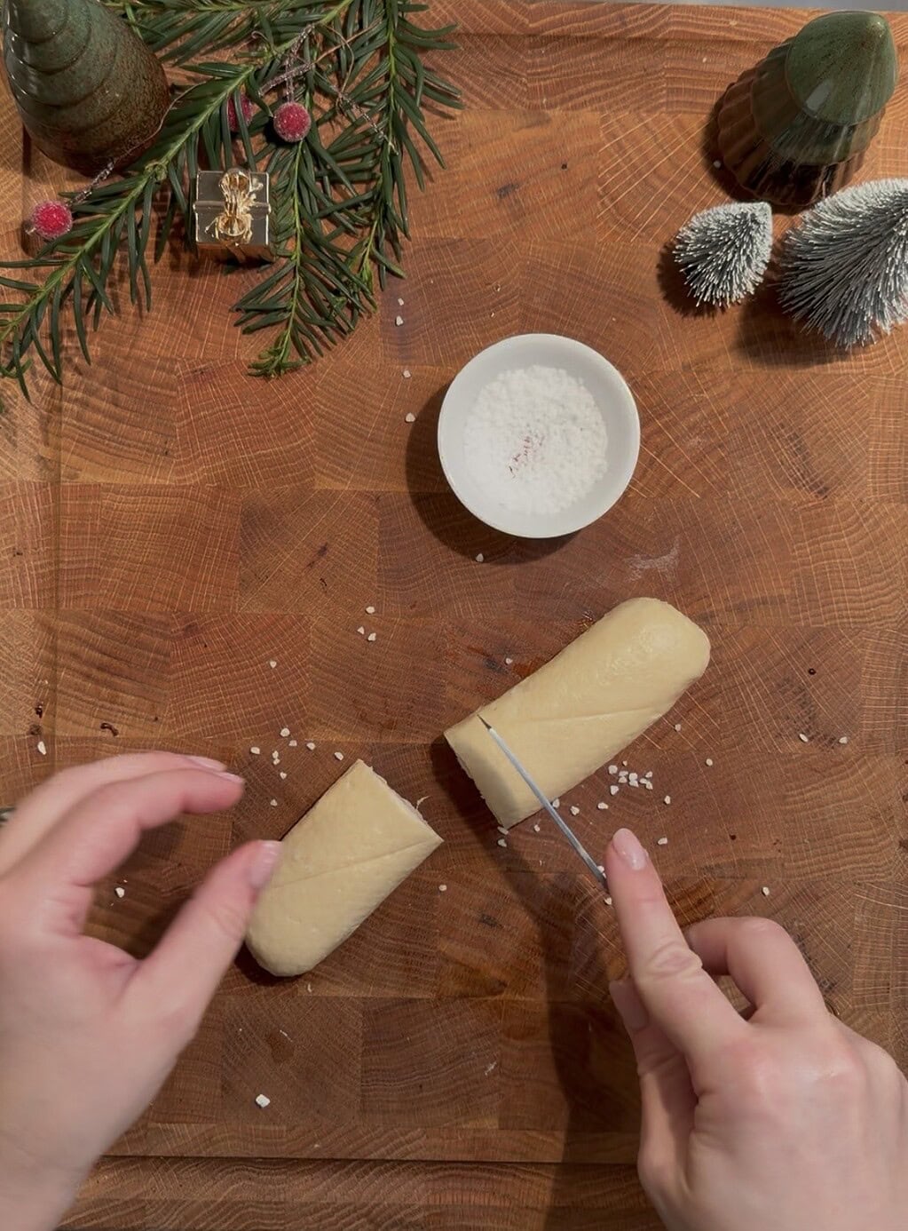 Frischer Teig und Salz auf Holzplatte, Weihnachtsdekoration im Hintergrund.