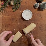 Frischer Teig und Salz auf Holzplatte, Weihnachtsdekoration im Hintergrund.
