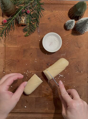Frischer Teig und Salz auf Holzplatte, Weihnachtsdekoration im Hintergrund.