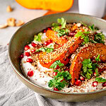 Geröstete Kürbisspalten mit Joghurt-Dip, Granatapfelkernen und Kerbel in einer Schale