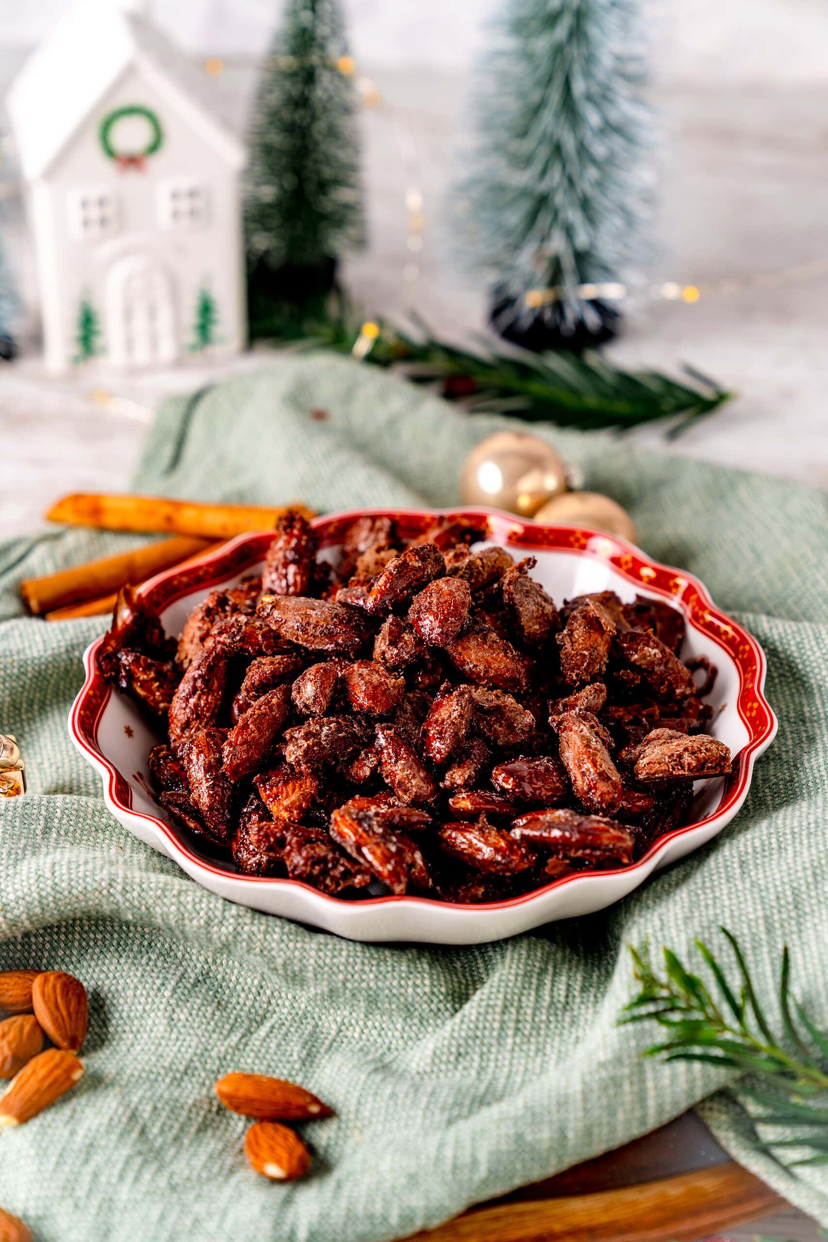 Gebrannte Mandeln aus der Heißluftfritteuse in einer Schale mit Weihnachtsmotiven auf einem grünen Tuch