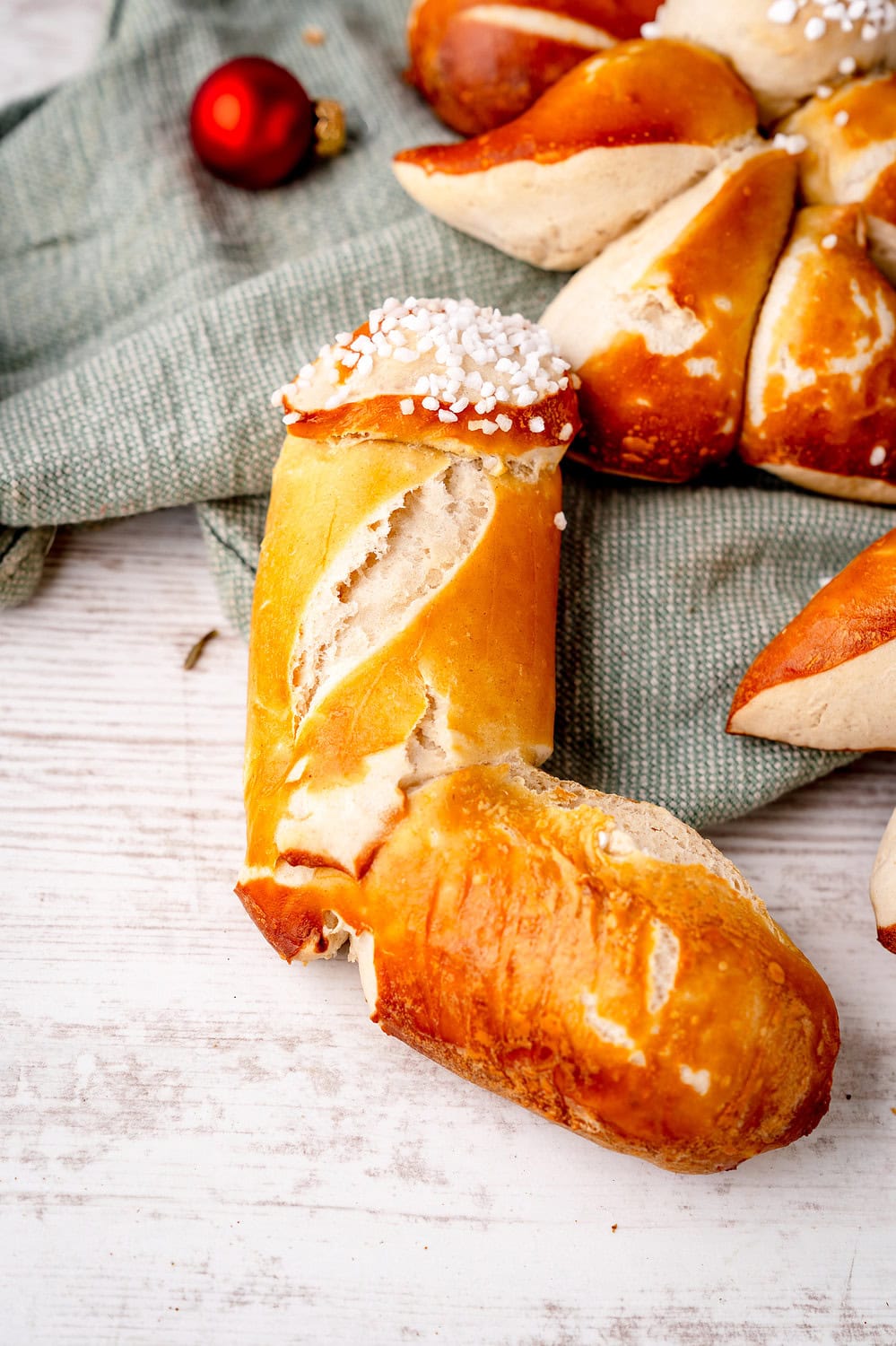 Fröhliches Laugengebäck mit Puderzucker auf weichem Tuch und Holzuntergrund. Nikolausstiefel