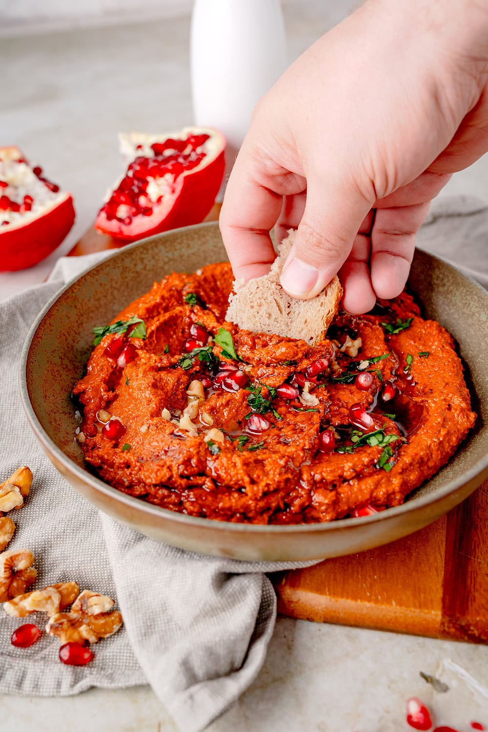 Hand fährt mit Brot durch den Paprikadipp mit Muhammara