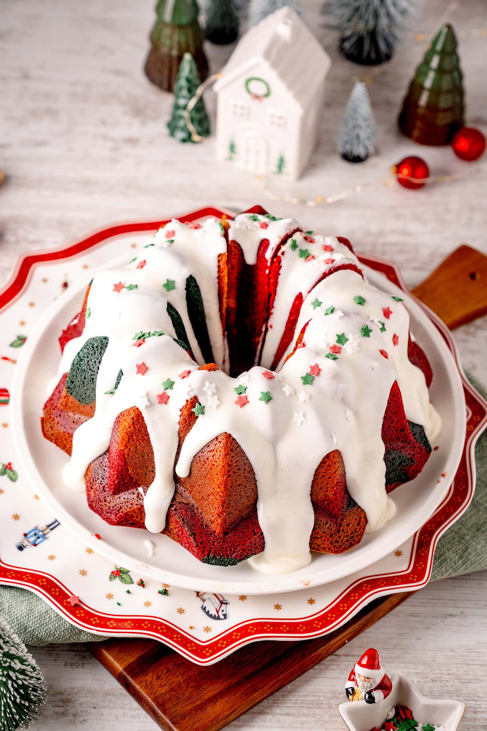 Weihnachtlicher Marmorkuchen in rot und grün mit weißem Zuckerguss auf einem Weihnachtsteller mit Weihnachtsdekoration
