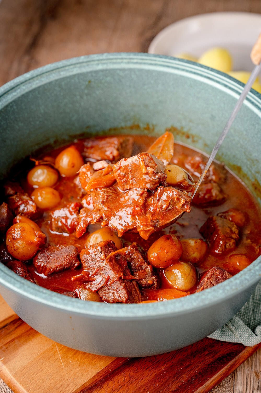 Stifado im Topf mit Perlzwiebeln, Lorbeer und einer dunklen Sauce.