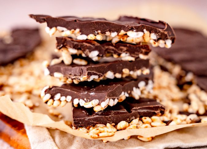 Nahaufnahme von Schokoladen Puffreis aus der Heißluftfritteuse, auf Holzbrett, weißem Tuch.