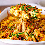 Ein Servierlöffel voller Mac and Cheese, wo der Käse Fäden zieht