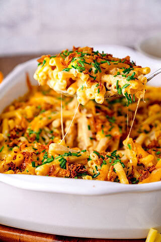 Ein Servierlöffel voller Mac and Cheese, wo der Käse Fäden zieht