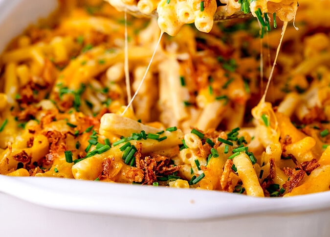 Ein Servierlöffel voller Mac and Cheese, wo der Käse Fäden zieht