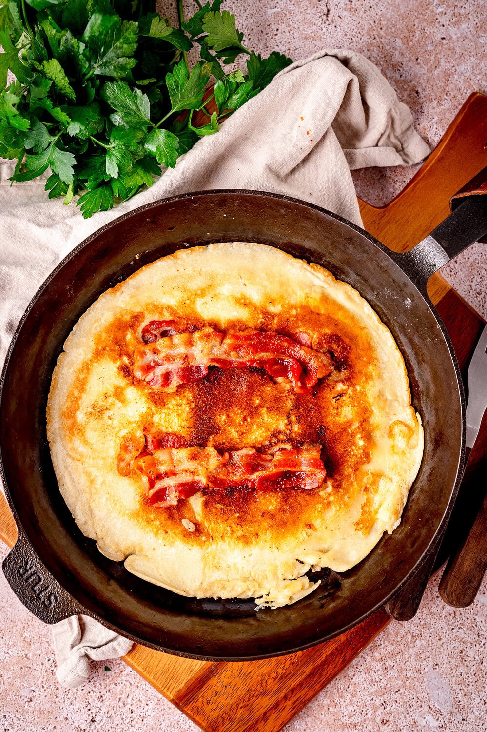 Dutch bacon pancake, in a cast iron pan, with crispy bacon.