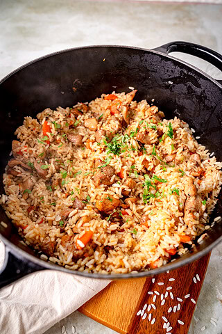 Plov mit Hähnchen in einem Gussbräter