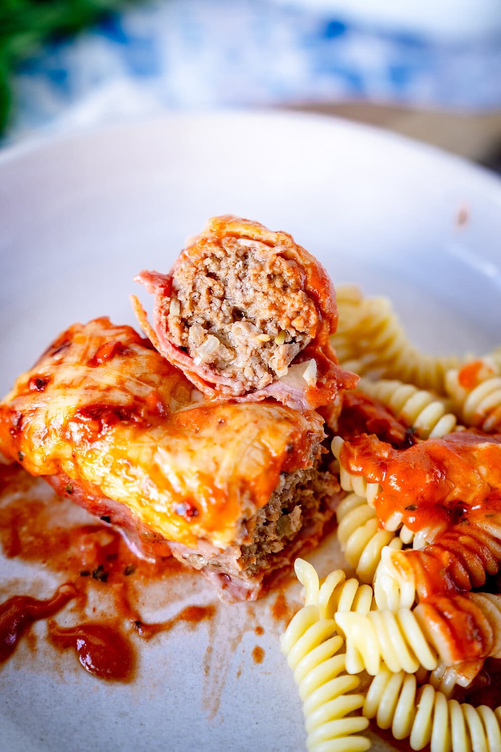 Sliced ​​minced ham rolls on a deep plate with pasta and tomato cream sauce