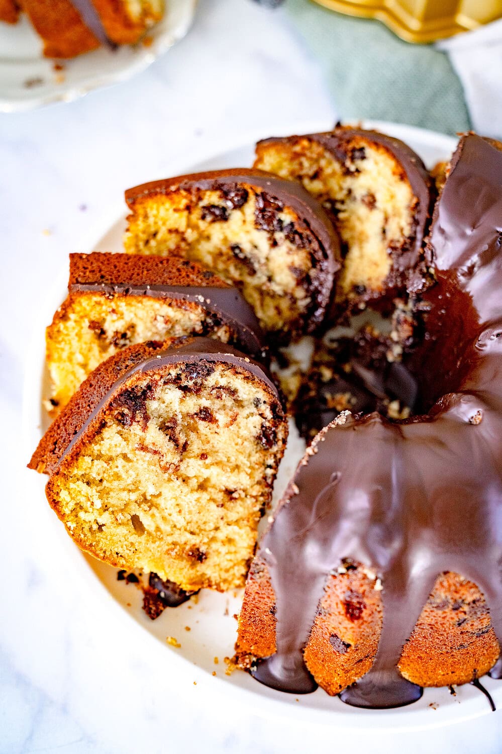 Sliced ​​chocolate chip cookie Gugelhupf on a cake plate with chocolate icing