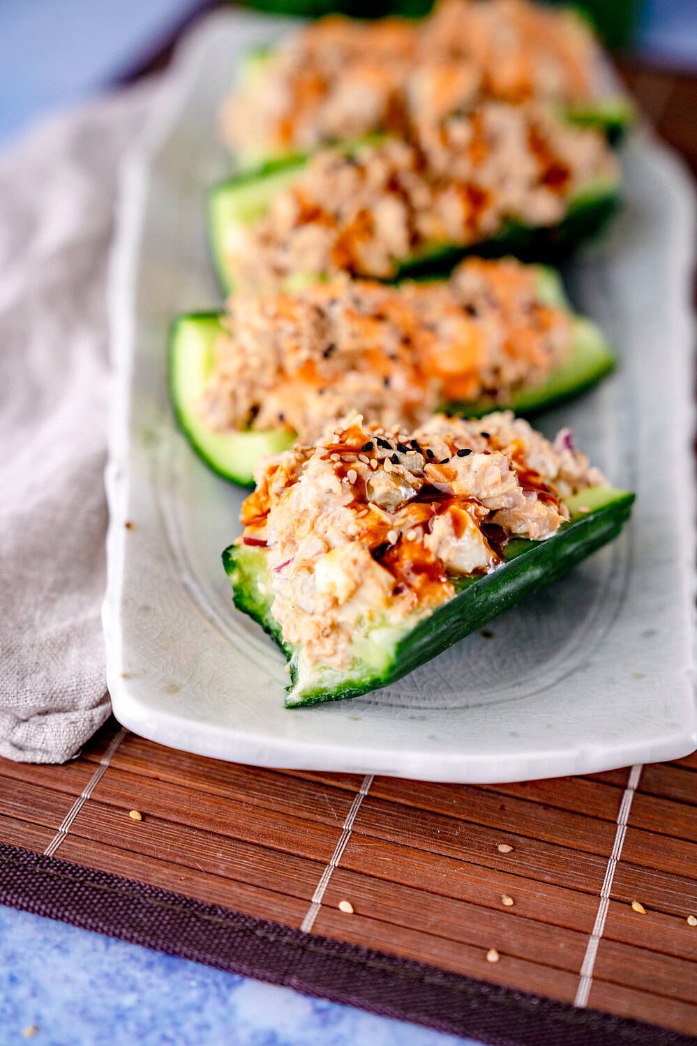 Half-eaten tuna and cucumber boat with cream cheese on a plate with sesame and soy sauce