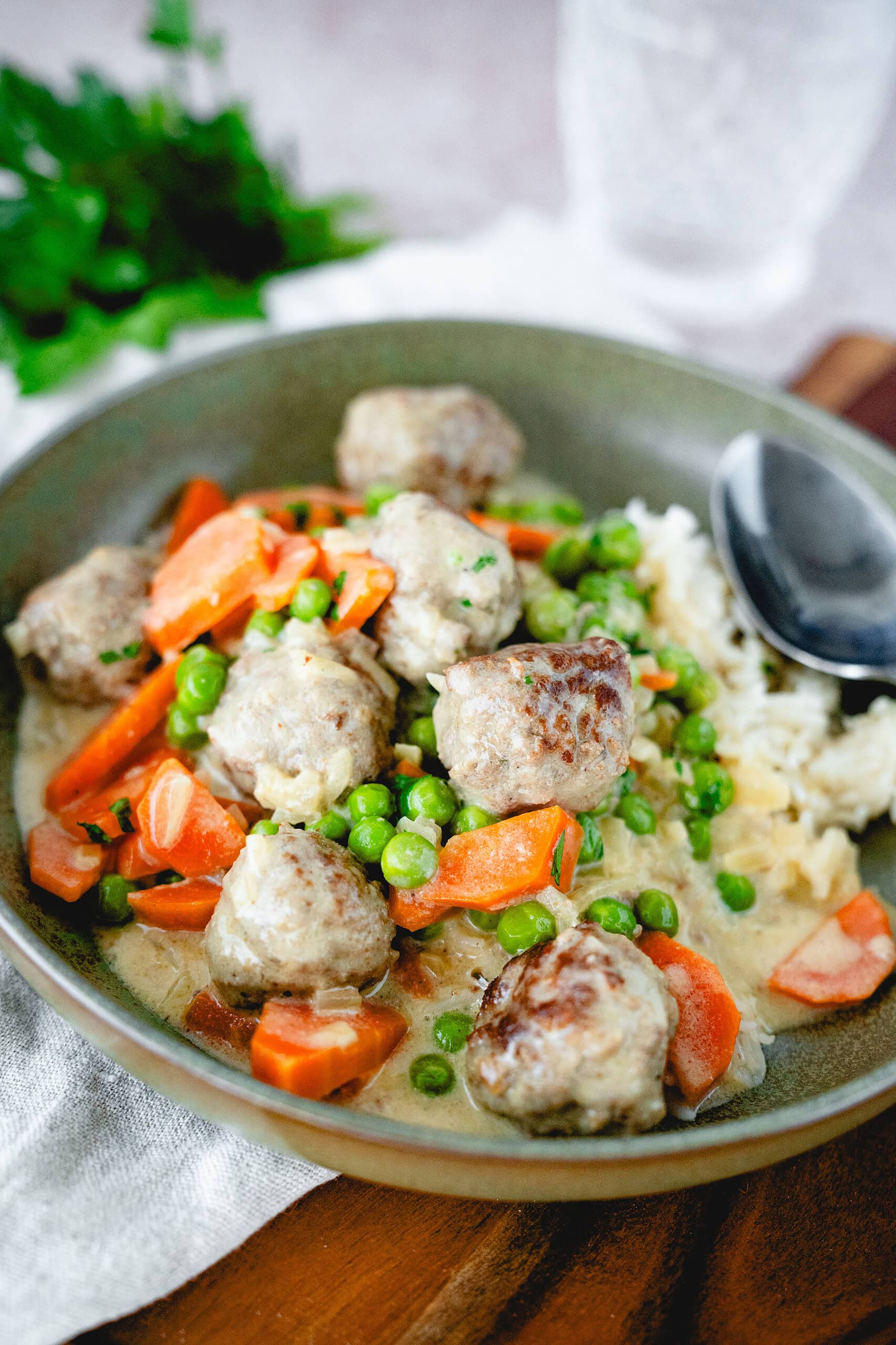 Saftig glänzende Fleischbällchen aus einem Wikingertopf mit Erbsen, Möhren und Rreis.
