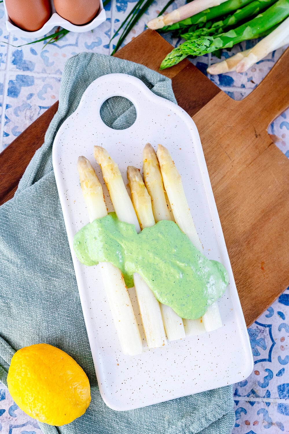Tartar sauce for white asparagus quickly and with wild garlic and parsley on an oblong white plate on a wooden board