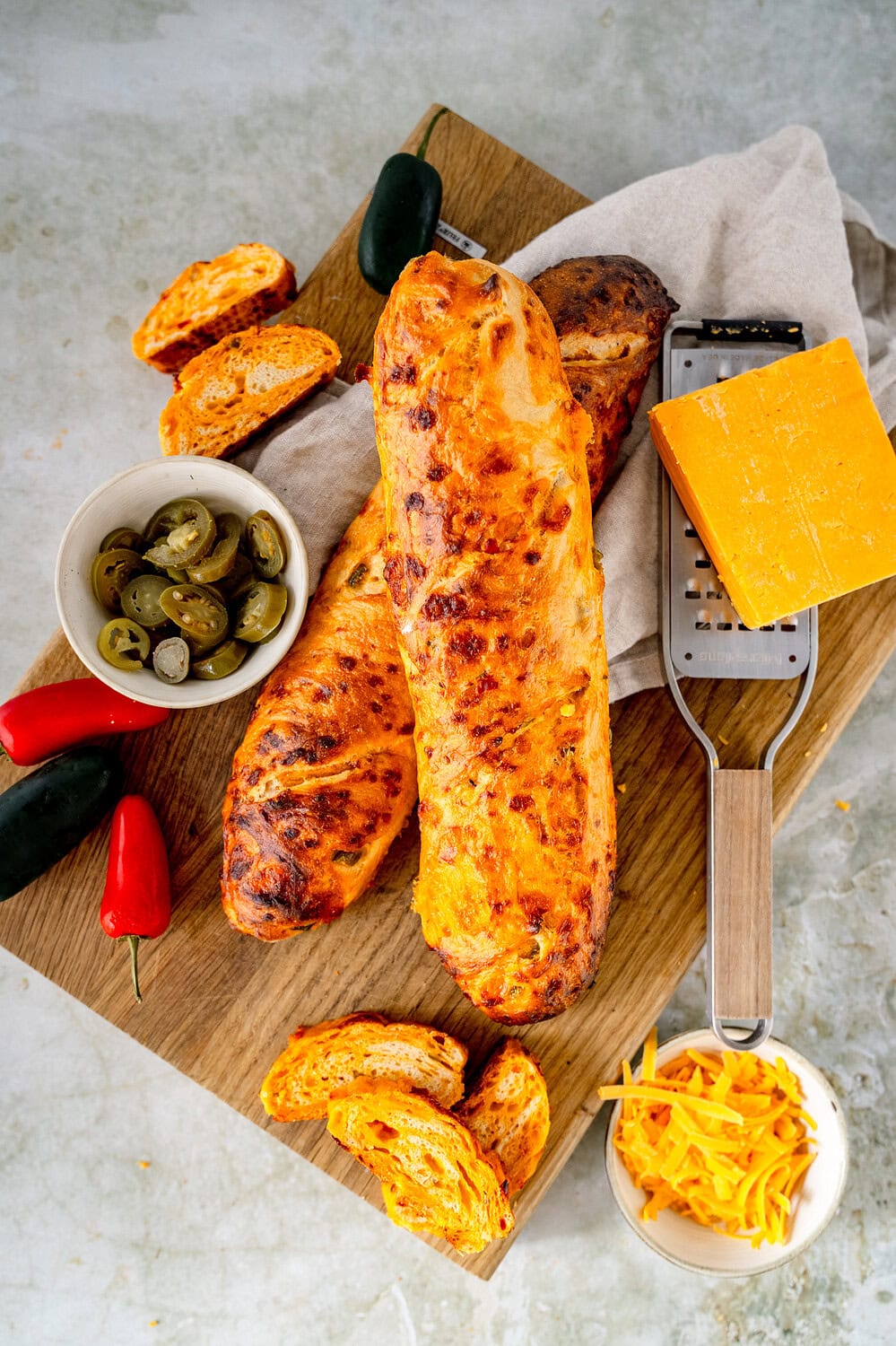 Top view of two chili cheese baguettes on a wooden board surrounded by the ingredients