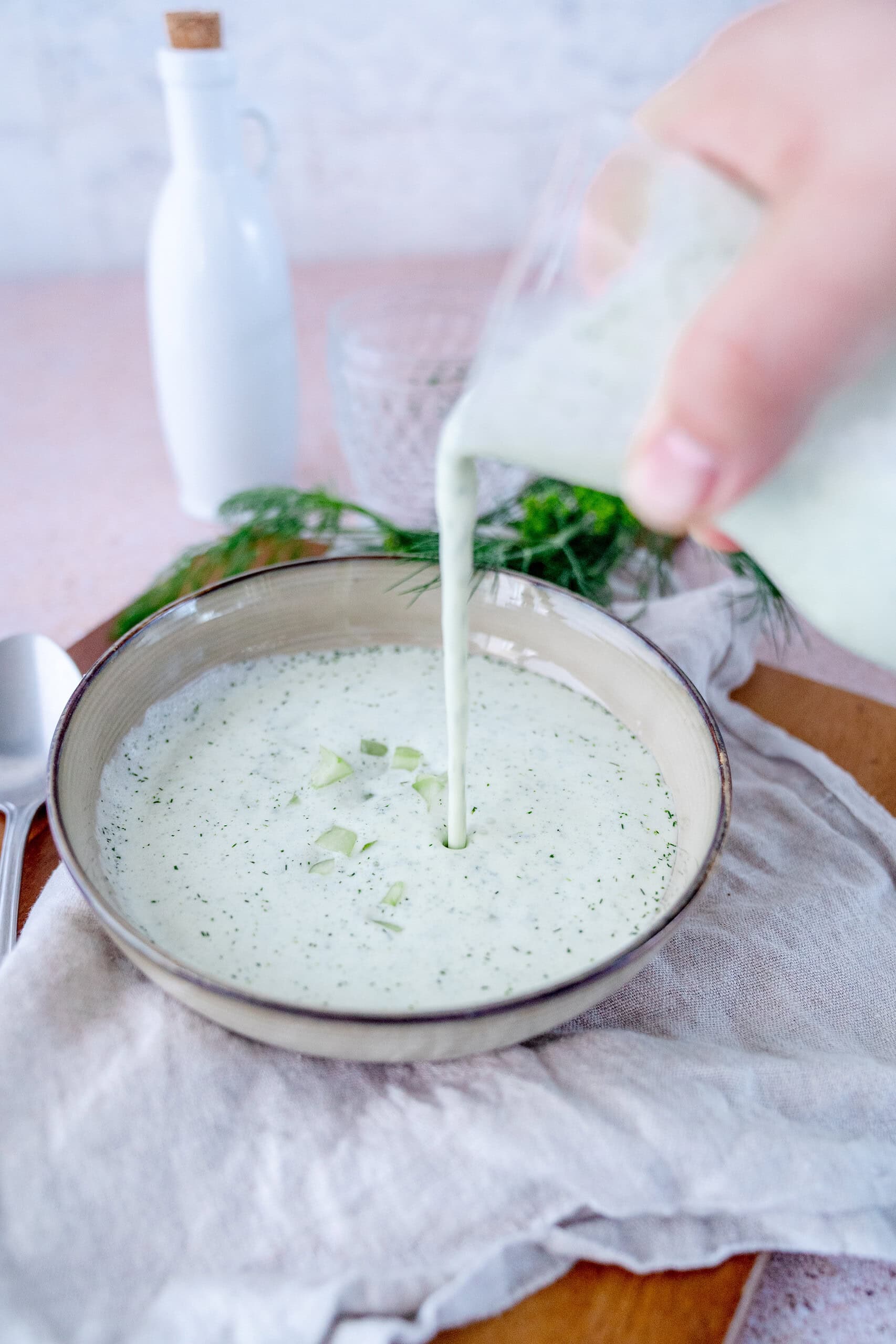 Kalte Gurkensuppe mit Minze wird in einen Suppenteller gegossen.