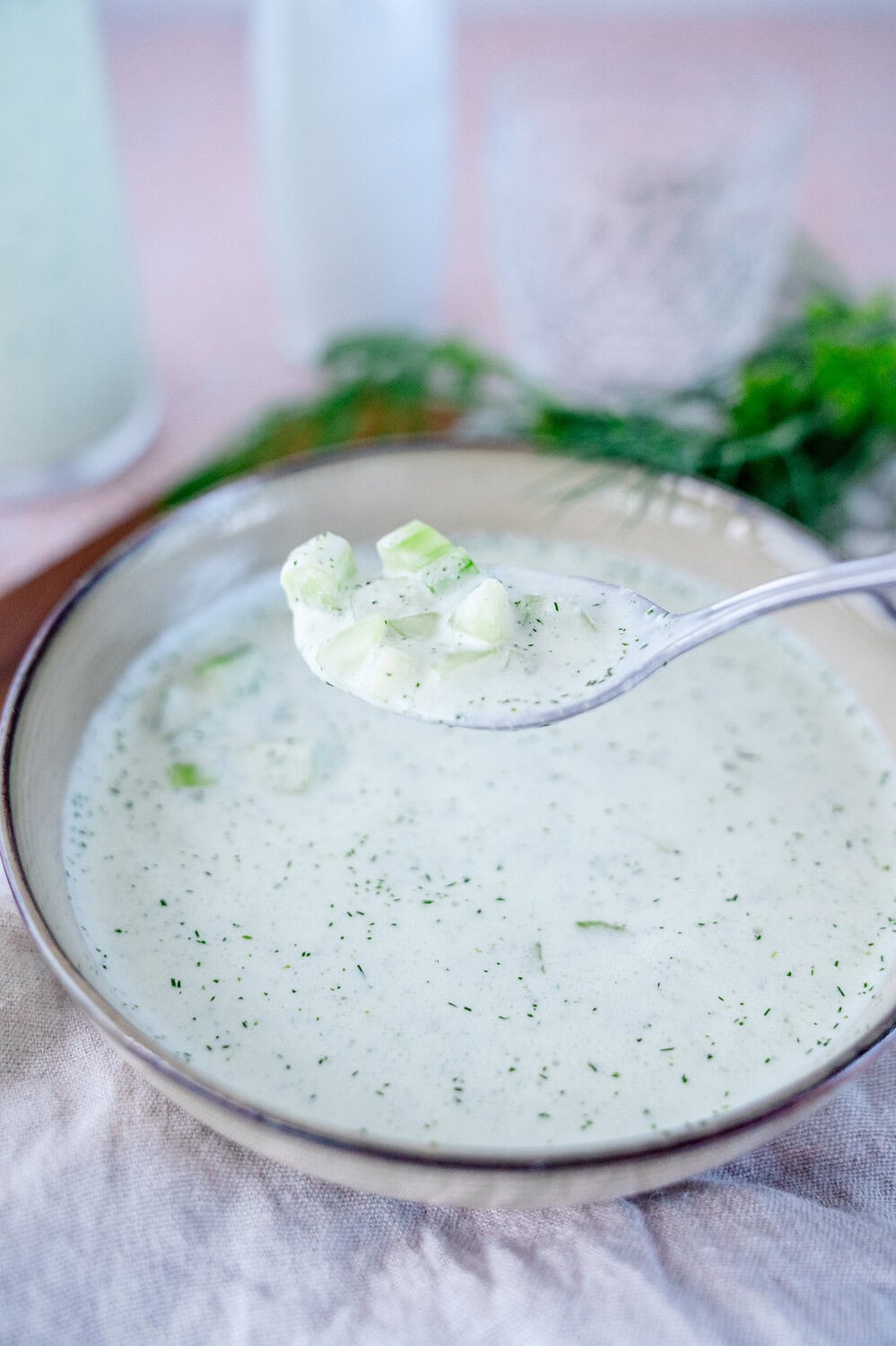 A spoonful of cold cucumber soup with small diced cucumber
