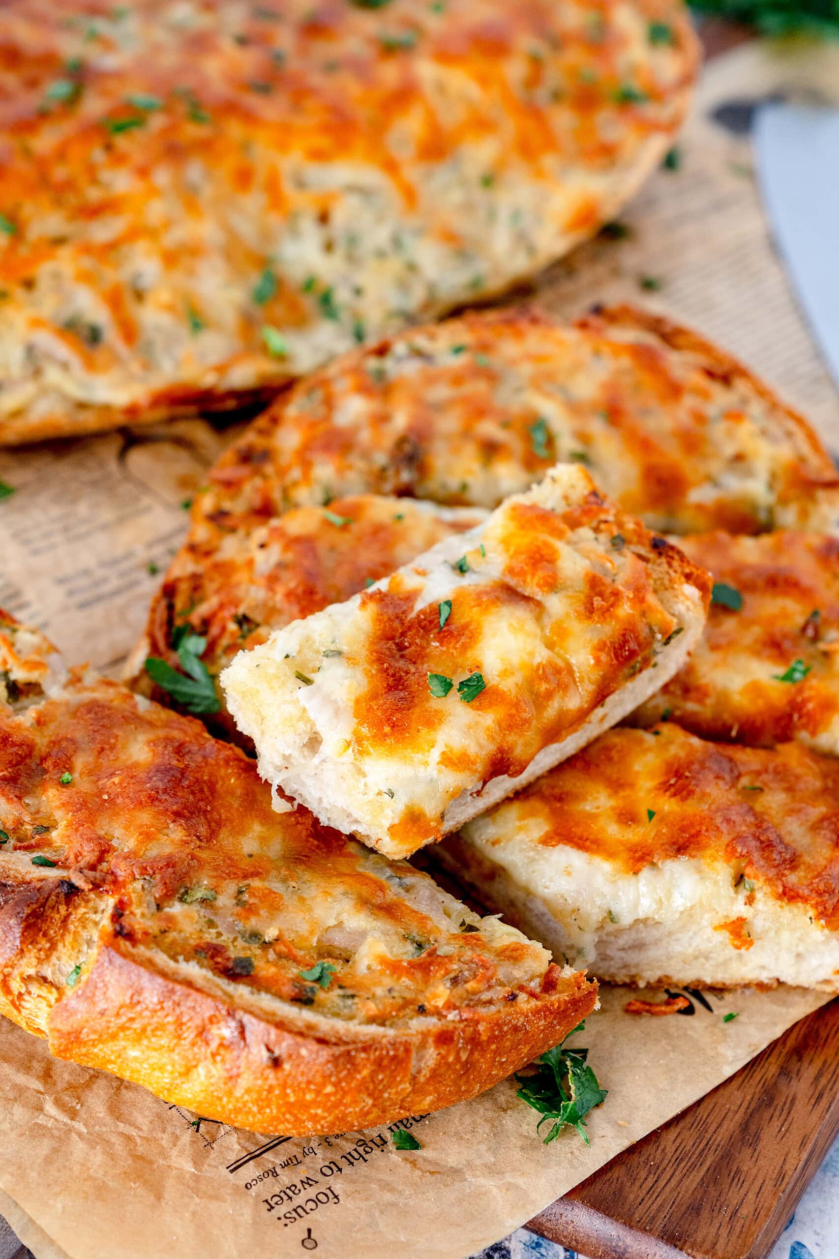 Knoblauch-Käse-Brot in Stücken angeschnitten auf Holzbrett