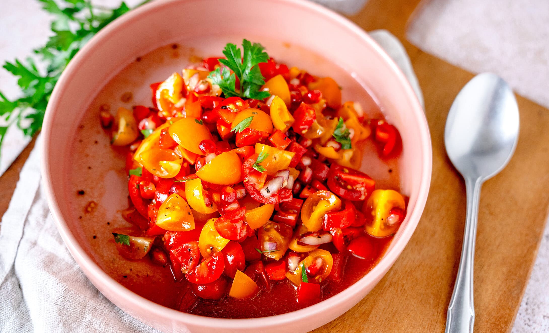 Tomaten-Granatapfel-Salat in einer weißen Schale.