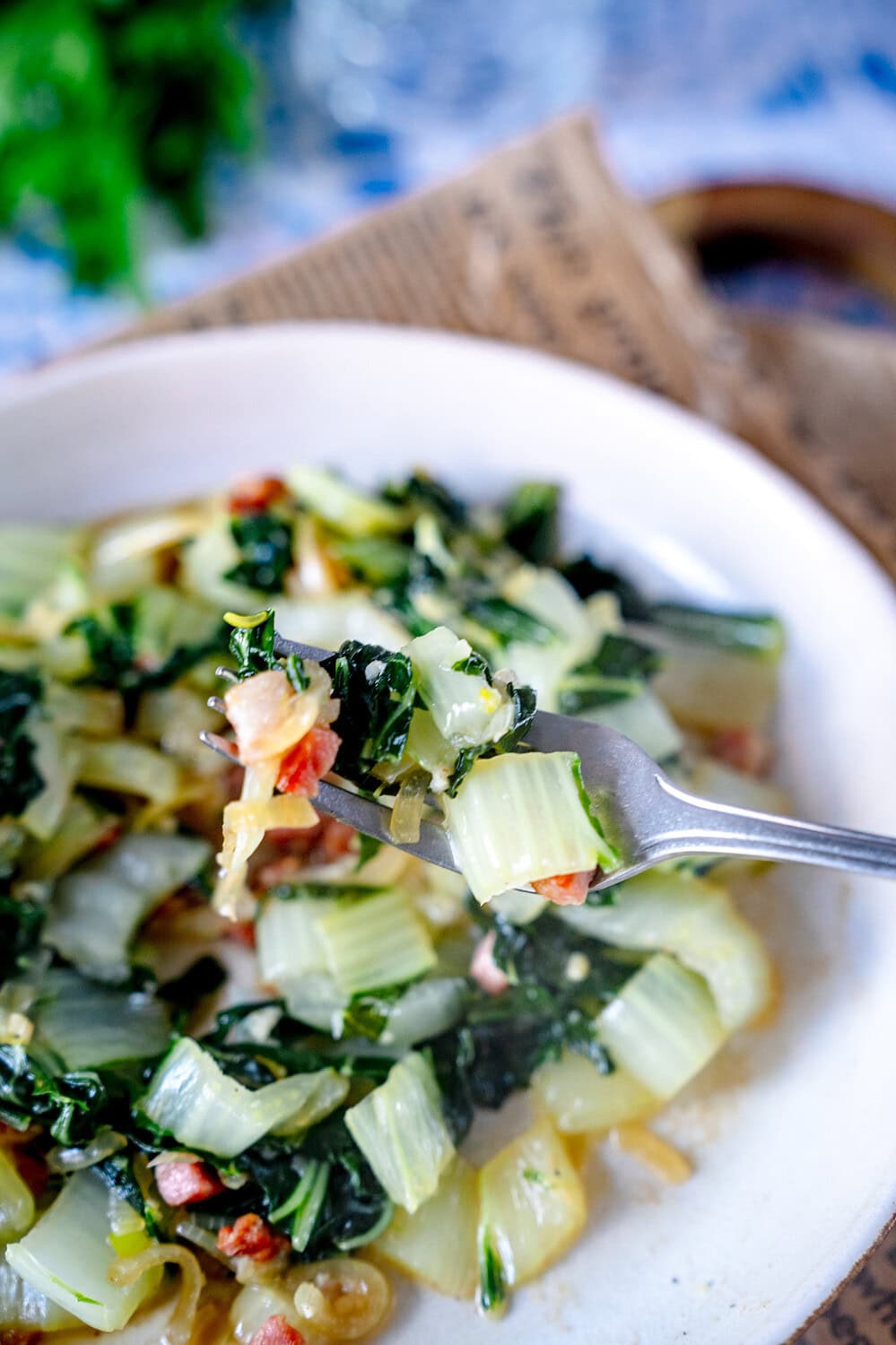 Pak Choi Pfannengemüse mit Speck auf einer Gabel.