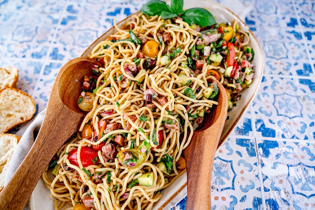 Salatschüssel aus der gerade mit Salatbesteck etwas rausgenommen wird.
