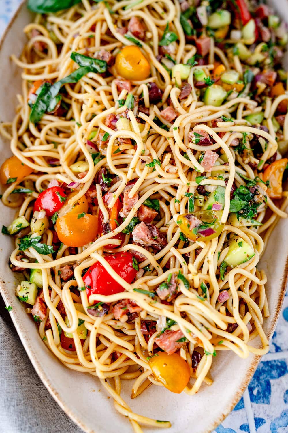 Nahaufnahme eines Salates aus Spaghetti mit Salami, Tomaten und Gurkenwürfeln