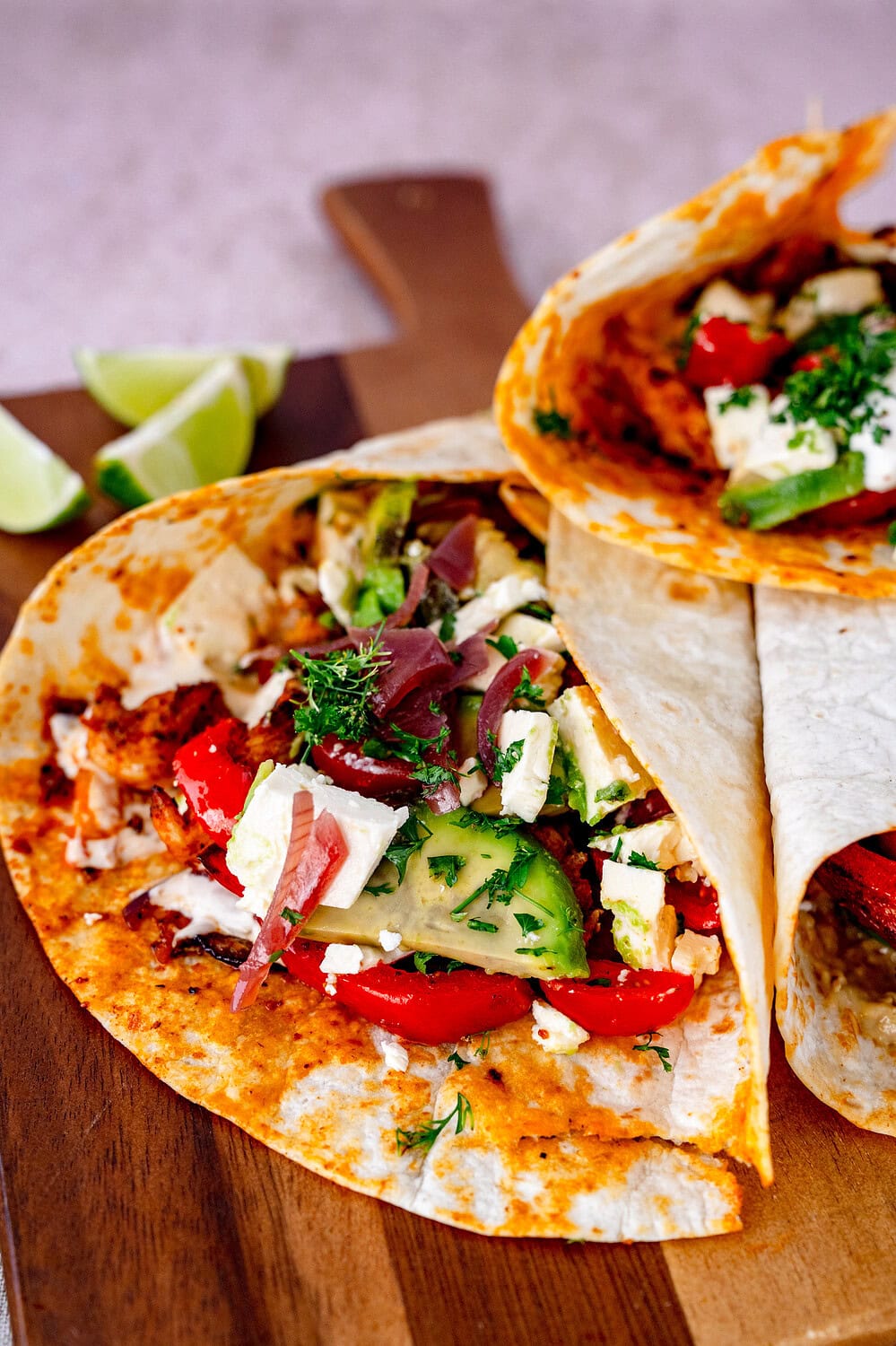 Nahaufnahme einer Hähnchen-Fajita. Man sieht die Tomaten, Feta, Avocado und die Fajita Hähnchen Füllung