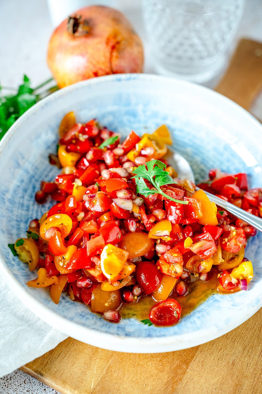 Leckerer Tomaten-Granatapfel-Salat in einem blauen Teller angerichtet.