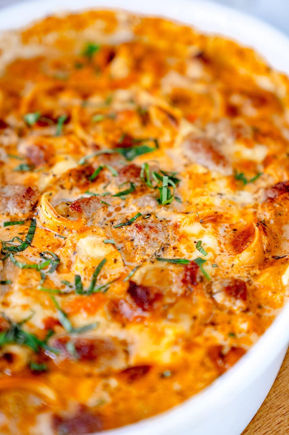 Nahaufnahme des Tortellinigratins mit Tortellini, Tomatensauce, Bratwurstbrät und kleingeschnittenem Basilikum