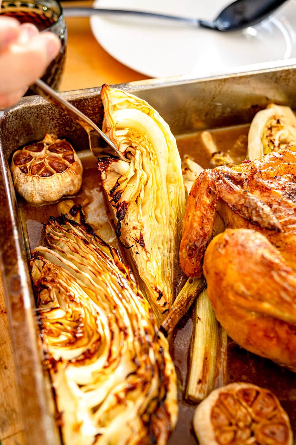 Gebackener Spitzkohl und Knoblauch neben Brathähnchen.