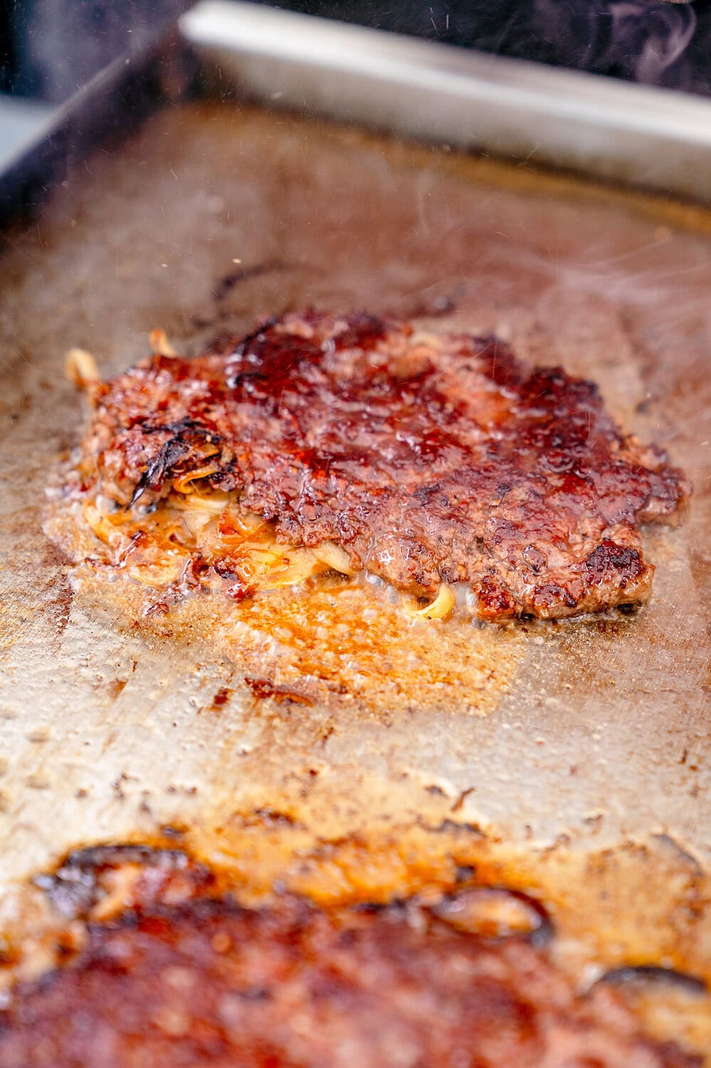 Die Zwiebeln vom Oklahoma Fried Onion Burger schmoren in Fleischsaft und Fett.