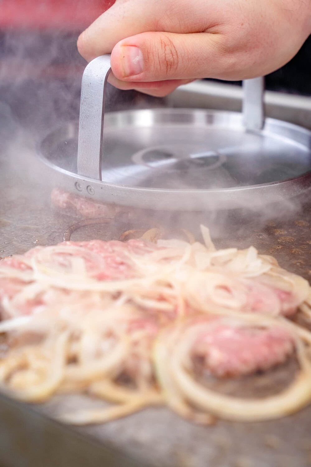 Die Zwiebeln werden für den Onion Burger ins Fleisch gesmashed
