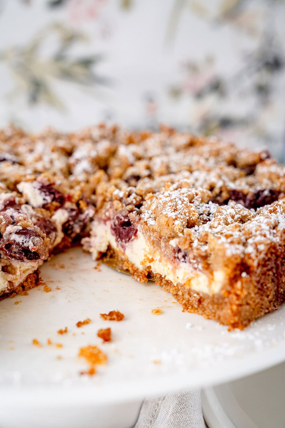 Angeschnittenes Kuchenstück vom Kirsch-Streuselkuchen mit einer Vanillecremefüllung